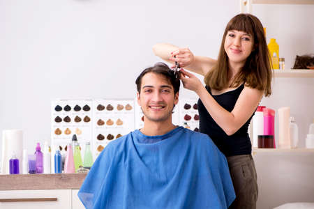 Young attracrive man visiting female barberの写真素材