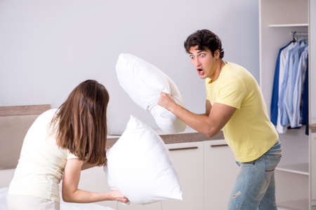 Wife and husband having pillow fight in bedroomの写真素材