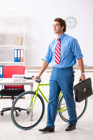 Young businessman using bike to commute to the officeの写真素材