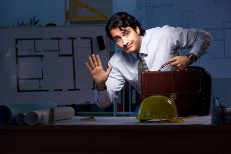 Young construction architect working on project at nightの写真素材