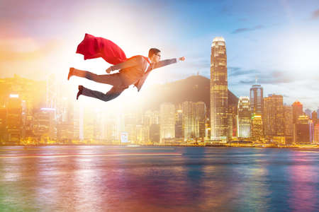 Superhero businessman flying over the cityの写真素材