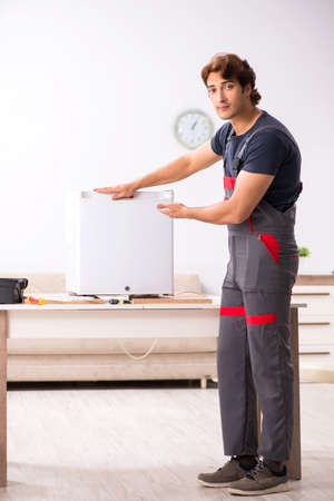 Young handsome contractor repairing fridgeの写真素材
