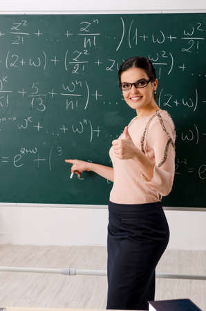 Female teacher standing in front of chalkboardの写真素材