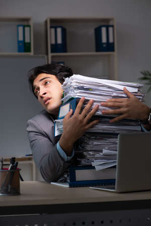 Young male employee working late at officeの写真素材
