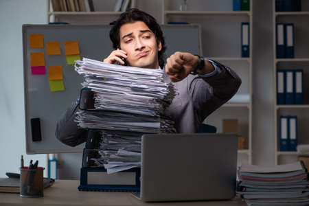 Young male employee working late at officeの写真素材