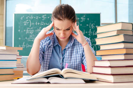 Female student with many books sitting in the classroomの写真素材