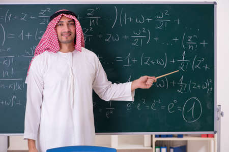 Arab teacher in front of chalkboardの写真素材