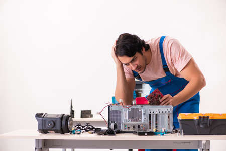 Young male contractor repairing computerの写真素材