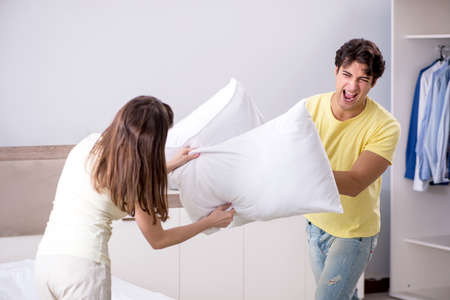 Wife and husband having pillow fight in bedroomの写真素材