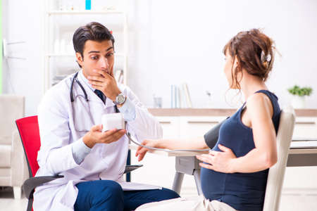 Young doctor checking pregnant womans blood pressureの写真素材