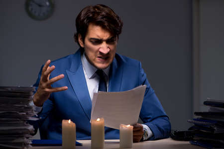 Businessman working late in office with candle lightの写真素材