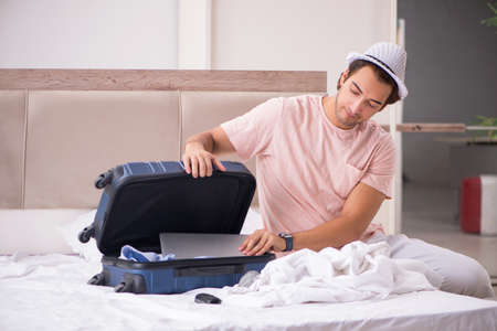 Man with suitcase in bedroom waiting for tripの写真素材