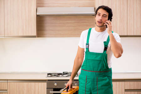Young contractor repairing oven in kitchenの写真素材