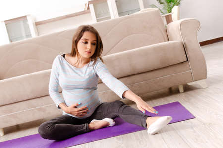 Young pregnant woman doing sport exercises at home