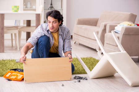 Young handsome man repairing chair at homeの写真素材