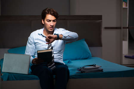 Tired businessman working overtime at home at nightの写真素材