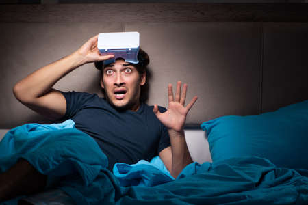 Young man playing computer games at night in bed