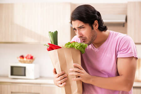 Young handsome man with vegetables in the kitchenの写真素材
