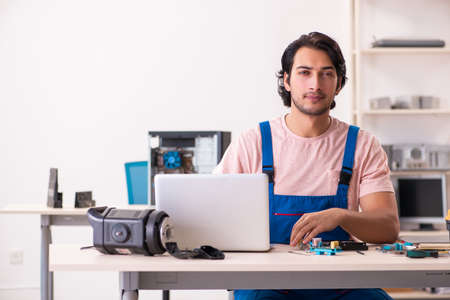 Young male contractor repairing computer