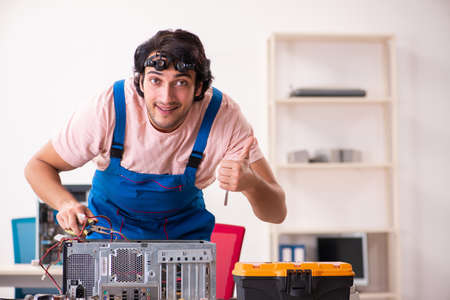 Young male contractor repairing computerの写真素材