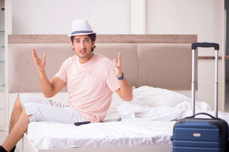 Man with suitcase in bedroom waiting for tripの写真素材