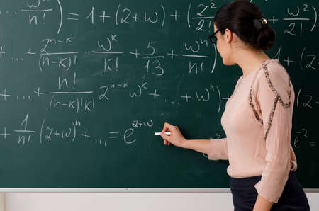 Female teacher standing in front of chalkboardの写真素材