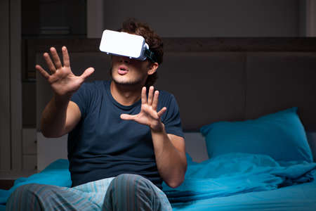 Young man playing computer games at night in bed