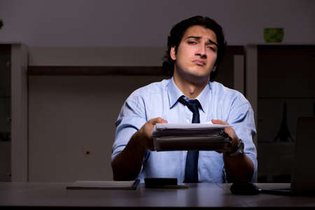 Young handsome employee and too much work in the officeの写真素材