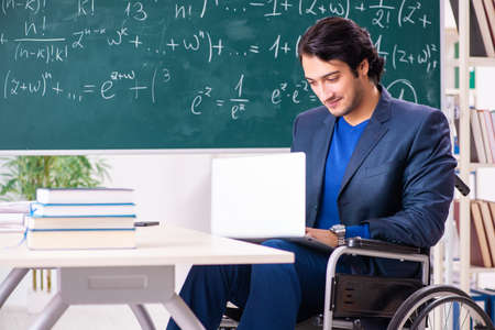Young handsome man in wheelchair in front of chalkboardの写真素材