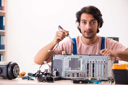 Young male contractor repairing computerの写真素材