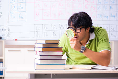 Young male student chemist in front of periodic tableの写真素材