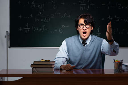 Young math teacher in front of chalkboardの写真素材