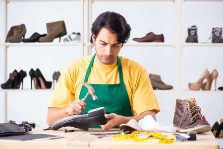 Young man repairing shoes in workshopの写真素材