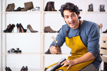Young man repairing shoes in workshop