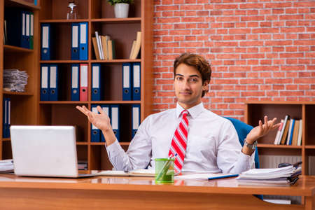 Young handsome employee sitting in the officeの写真素材