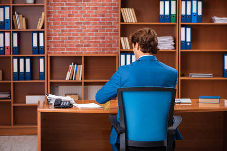 Young handsome employee sitting in the officeの写真素材
