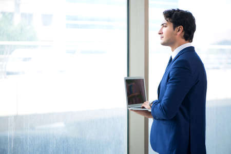 Young handsome businessman standing at the windowの写真素材