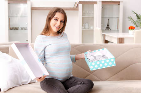 Young pregnant woman sitting on the sofa at homeの写真素材