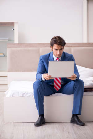 Young employee working at home sitting on the bedの写真素材