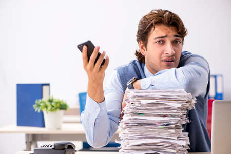 Young handsome employee unhappy with excessive workの写真素材