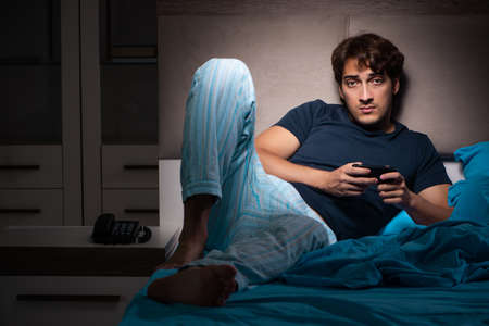 Young man texting on mobile late at nightの写真素材