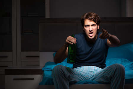 Man drinking in the bed under stress
