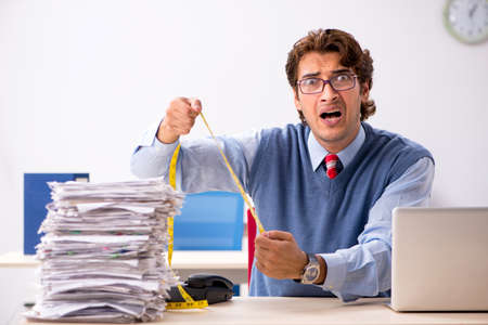 Young handsome employee unhappy with excessive workの写真素材