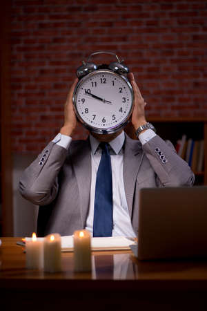 Businessman working late in office with candle lightの写真素材