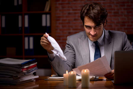 Businessman working late in office with candle lightの写真素材