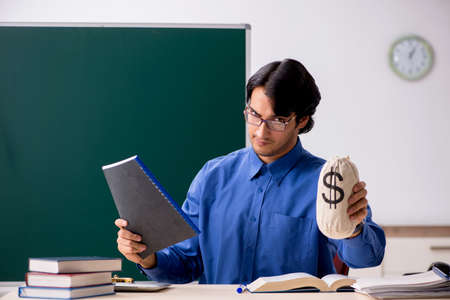 Young male teacher in front of chalkboardの写真素材