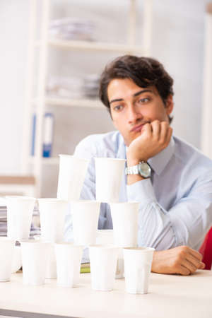 Young employee building pyramid from plastic cupsの写真素材