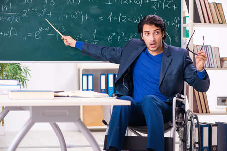 Young handsome man in wheelchair in front of chalkboardの写真素材