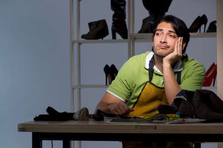 Young shoemaker in workshop at night