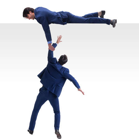 Businessman offering helping hand to falling colleagueの写真素材